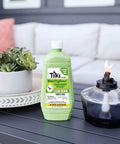 Clean Burn Mosquito Repellent Torch Fuel For Outdoor Use Easy Pour One Quarter Gallon 32 Oz Smokeless Low Soot Citronella Plant Based Formula Works With All Torches Patio Garden Backyard bottle on table next to torch.