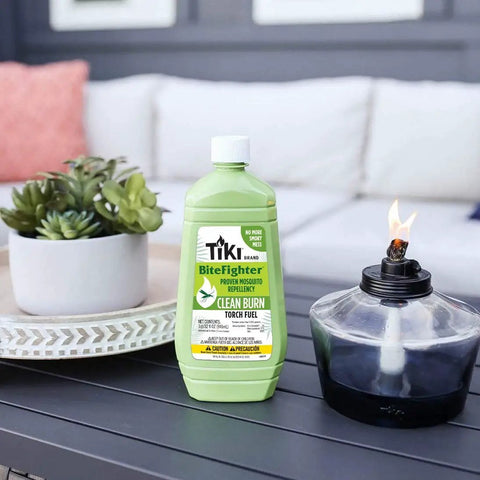 Clean Burn Mosquito Repellent Torch Fuel For Outdoor Use Easy Pour One Quarter Gallon 32 Oz Smokeless Low Soot Citronella Plant Based Formula Works With All Torches Patio Garden Backyard bottle on table next to torch.