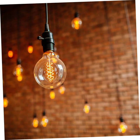 Close-up of a hanging light bulb with glowing filament in a brick-walled room, focus on 20 Pcs Black Ul Twist Lamp Turn Knobs Replacement.