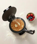 Leefasy Electric Pancake Maker With Nonstick Round Plate And Stainless Steel Construction cooking a pancake with berries on a side.