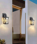 Two Pack Dusk To Dawn Outdoor Wall Lanterns With Photocell Sensor mounted on house exterior, aluminum black finish, clear glass