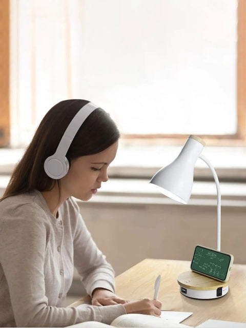 Woman studying beside a Metal Desk Lamp With Fast Wireless Charging Pad And USB Ports, Arc Table Light, 3 Way Dimmable, in white finish.