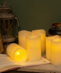 Flickering Flameless LED Candles Real Wax Pillar Set Of 6 with warm glow, 5 inches tall by 3 inches wide, displayed on a table.