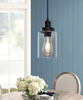 Industrial Pendant Lighting Set With Clear Glass Shade hanging above a dining table, showing the illuminated bulb and matte black finish.