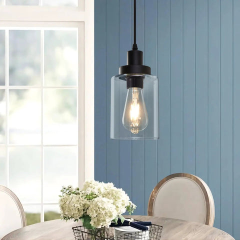 Industrial Pendant Lighting Set With Clear Glass Shade hanging above a dining table, showing the illuminated bulb and matte black finish.