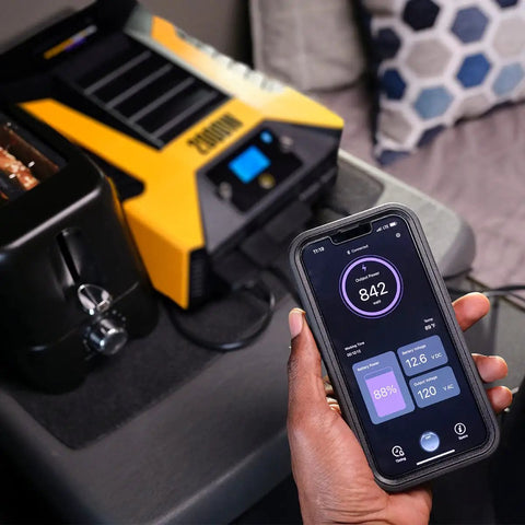 Professional 2000 Watt Power Inverter For Cars And Trucks Featuring Bluetooth Remote And Fast Charge Usb C Ports To Keep Your Devices Juiced Up Without Breaking A Sweat On Long Drives next to a smartphone displaying output power.