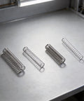 Top Tier 300 Piece Compression Spring Assortment Kit With 23 Sizes And Premium 304 Stainless Steel Construction Perfect For DIY Repairs, Automotive Maintenance, And Household Mechanical Jobs That Need Reliable Springs You Can Trust Every Single Time., four stainless steel compression springs on a work surface