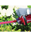 Person using Pwr Core 20 22 Inch Cordless Hedge Trimmer Kit With 2Ah Battery And Charger on garden bushes.