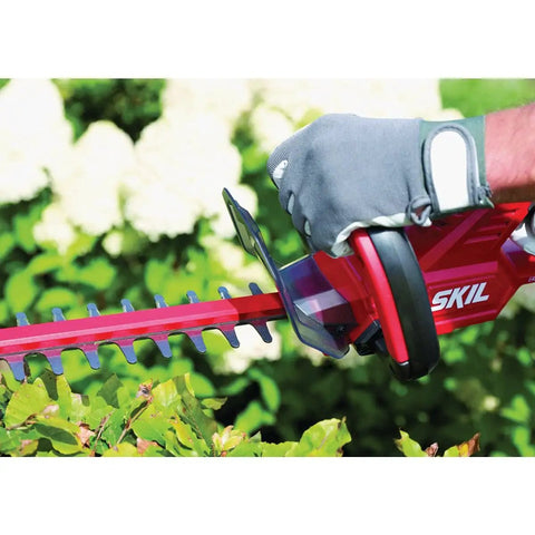 Person using Pwr Core 20 22 Inch Cordless Hedge Trimmer Kit With 2Ah Battery And Charger on garden bushes.