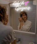 Woman applying makeup under 'Hello Gorgeous' Birthday Gift Neon Sign With White And Pink Glow That Lights Up Your Home Romantic Wall Decor For Any Room Eye Catching Lit Party Lighting Sweet Gift Idea For Celebrations And Cozy Night In Vibes