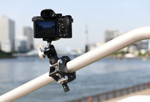 Savior Clamp With Articulated Jaws, 66 Lb Max Load, mounted on a railing holding a camera, anodized aluminum, silver finish.