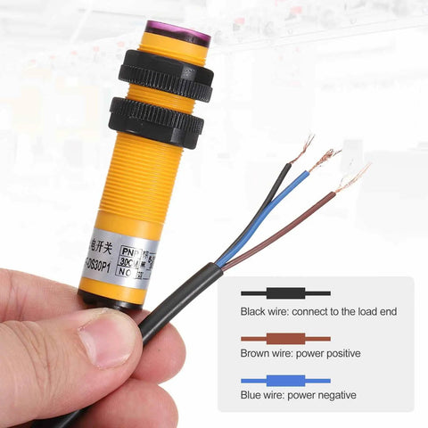 Person holding E3F DS30P1 Photoelectric Sensor with exposed wires, yellow M18 housing