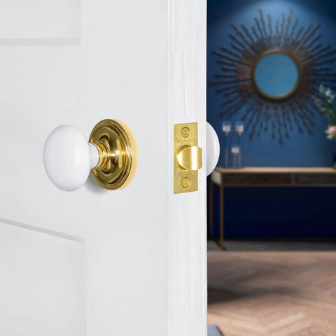 Old School Classic Rosette White Porcelain Round Door Knob For Interior Doors installed on white door with brass finish