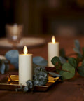 Outdoor Flameless LED Votive Candle Set of 2, Ivory 1.5 x 4 Inches, Moving Flame, on a tabletop with greenery decoration