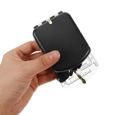 Hand holding black Orienteering Compass With Scale And Mirror Mini Ultralight Hiking Survival Tool for Camping and Backpacking