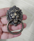 Antique Bronze Lion Head Ring Pull Cabinet Handles Set Of 4 With Screws, 2.6 Inches Long By 1.6 Inches Wide, shown in hand