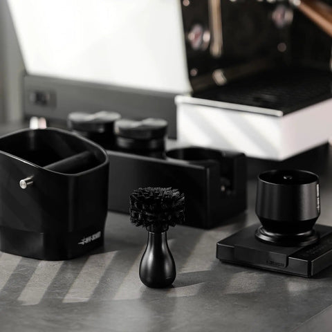 Pro-Grade Espresso Portafilter Brush For 51mm, 54mm, And 58mm Baskets, ABS handle, with arc cross bristles on a kitchen counter.