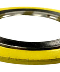 Close-up of spiral-wound gasket with yellow outer ring and silver inner metal ring.