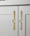 Close-up of Vintage Cabinet Pulls 3 Pack Wave Handles in gold on white cupboard doors, solid metal hardware with retro charm.