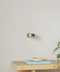 Three Pack Wireless Battery Operated Picture Lights With Remote And Timer For Art Frames No Sweat Install Killer Glow Smooth Dimming In Gold Finish, mounted on wall with plant and decor.