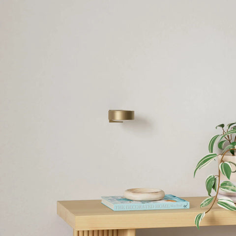 Three Pack Wireless Battery Operated Picture Lights With Remote And Timer For Art Frames No Sweat Install Killer Glow Smooth Dimming In Gold Finish, mounted on wall with plant and decor.