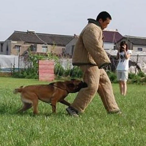 Trainer wearing Durable Dog Training Suit For Bite Protection Unisex Protective Clothing with dog biting leg in outdoor field