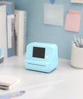Rock This Slick AI Voice Mini Thermal Printer With Bright Display And Awesome Creative App For Kids Speech To Line Art Drawing Anime Sketch And Hype Storytelling Portable Prints on a desk.