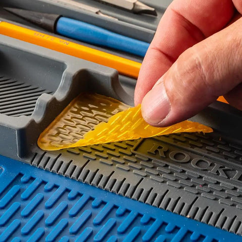 Hand removing glue from Silicone Project Tray Flexible Catch All Organizer For Small Parts Portable Tool Tray With Compartments
