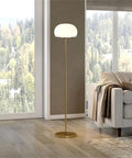 Tall Floor Lamp With Glass Mushroom Shade In Brass And White Milk Glass beside sofa in living room with forest view.