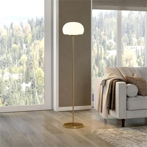 Tall Floor Lamp With Glass Mushroom Shade In Brass And White Milk Glass beside sofa in living room with forest view.