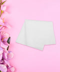 Top Shelf White Cleanroom Wiper Cloth For Flawless Camera Lenses Phone Screens Smart Watches And Eyeglasses Straight Up Dust Free Nano Microfiber on pink backdrop with faux flowers.