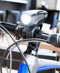 Close-up of Lumina 1000 Boost Front Bike Light mounted on handlebars for mountain, road, and city commuting, water-resistant design.
