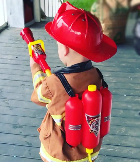 Child wearing a red helmet and firefighter outfit using Firefighter Backpack Water Blaster For Kids, 1.3L Tank Hose Shooter.