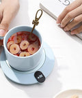 Compact Desk Coffee Warmer With Auto Shut Off And Waterproof Aluminum Base Keeps Your Morning Brew Steaming All Day with a blue cup and spoon.