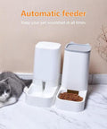 Automatic pet feeder with food and water next to a gray and white cat on a tiled floor.