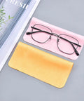 Two microfiber eyeglass cleaning cloths, pink and yellow, with a pair of glasses on the pink cloth.