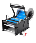 Velorantia Automatic Bottle Labeling Machine For Round Pet Glass Containers With Handle Compact Design For Small Business Use Adjustable Clamps Fits Wide Range Of Label Sizes And Bottles Easy Setup view from the side showing the label dispensing mechanism.