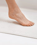 Foot stepping on Softex Bath Mat For Tubs 17 By 36 Inches Taupe Machine Washable Skid Resistant With Suction Cups And Drain Holes