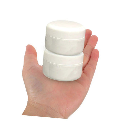 Hand holding two white containers of Two Piece Tile Repair Kit With Pro Grade Ceramic Paste Quick Dry Grout Filler.