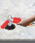 4-inch pneumatic wet stone polisher with red handles and silver body, air hose attached, on marble surface.