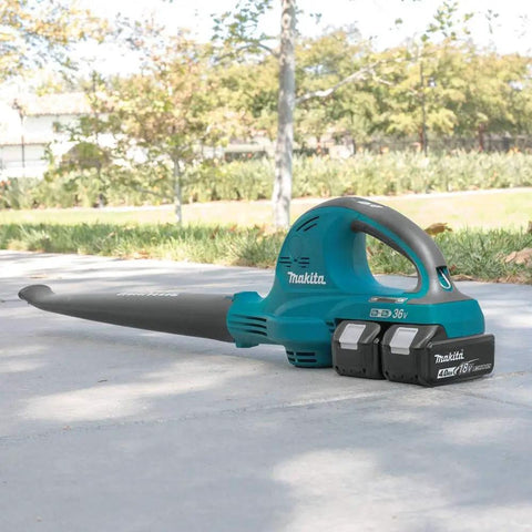 Badass 36V Cordless Leaf Blower Kit Cracks Yard Mess With Two 18V Batteries Pushing 155 CFM And 208 MPH Air Blast For Outdoor Cleanup Zero Hassle Brushless System Powers Long Sessions And Smooth Debris Clearing on a path with grass in background.