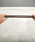 Hands adjusting the curved tension shower curtain rod with pivoting flanges no drill installation old world bronze finish