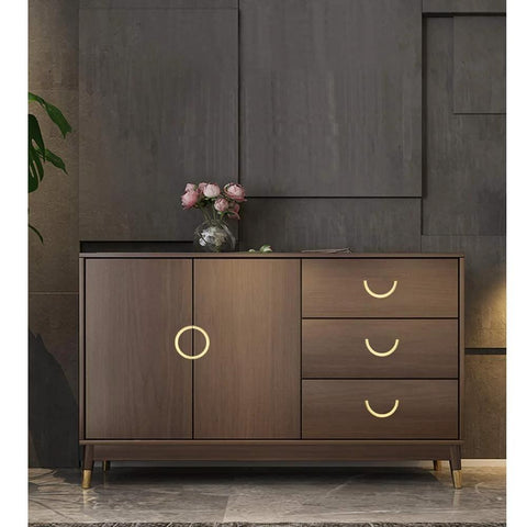 Stylish cabinet with golden copper hardware handles, wooden finish, three drawers, and decorative flowers on top.
