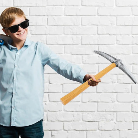 Child holding a Lightweight Foam Pickaxe Prop For Halloween Cosplay And Stage Performances, 19.29 Inch Cross Tool Toy against brick wall.