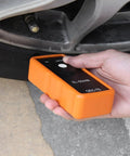 Tire Pressure Monitor System Relearn Tool El-50448 Orange Grip Battery Powered Sensor Reset Kit For Gm Vehicles in hand near tire valve.