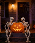 Indoor Halloween Skeletons Two Pack 15 Inch Life Size Full Body Posable Joints Skeleton Figures For Spooky Home Decor Realistic Resin Bone Color Dress Up Ready For Parties And Year Round Halloween Vibe with sitting skeletons and jack-o'-lantern on porch