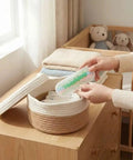 Person placing soft cotton cloths into woven basket on wooden dresser near window, with stuffed bears in the background.