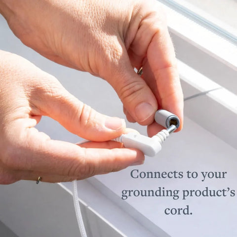 Close-up of hands attaching a white grounding cord plug to a gray earthing stake adapter.
