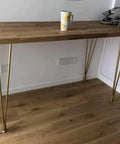 Heavy Duty 28 Inch Gold Hairpin Table Legs With Adjustable Leveling Bolts holding a wooden tabletop and a cup.