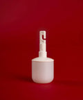 White plastic object with a small hook on top, standing on a red background.